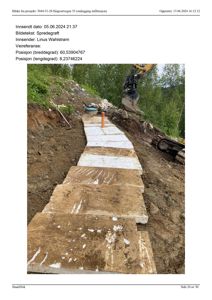 Fotografi av en byggeplass som viser et utgravd grøft med en grøftmaskin (spredegrøft) i arbeid. Det er lagt ned hvite plater i bunnen av grøften.