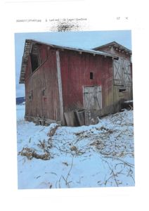 Fotografi av en gammel, rød trebygning (kanskje en uthus eller skur) i snø.