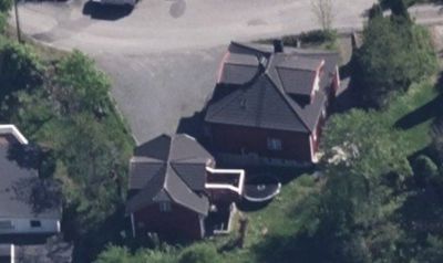 Luftfoto av to bolighus sett fra oven, med omgivende trær og vei.