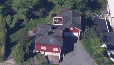 Luftfoto av en rød villa med mørkt tak, sett fra oven. Bildet viser bygningens form, omgivelser og nabolag.