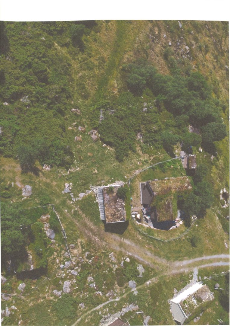 Luftfoto av et eksisterende bygganlegg på en grønn, kupert tomt.