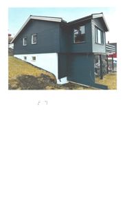 Fotografi av en mørkeblå, toetasjes bolig sett fra siden. Bildet viser fasaden, vinduer, tak og grunnmur.