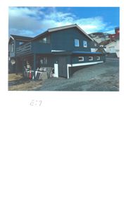 Fotografi av en mørkeblå, toetasjes bygning med en stor balkong på første etasje, sett fra en skrå vinkel.