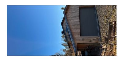 Fotografi av en bygning med trefasade og garasjeport sett fra utsiden.