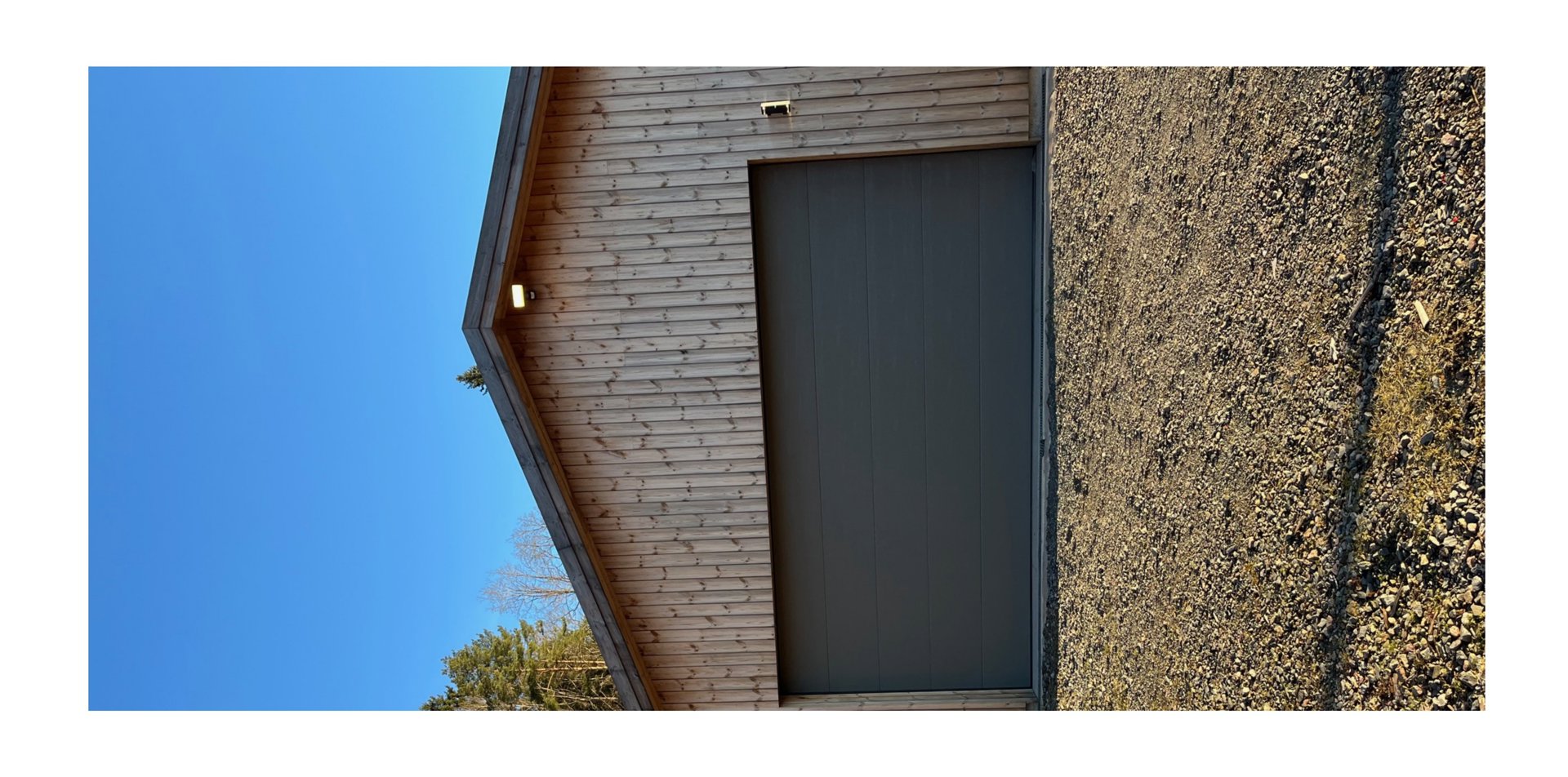 Fotografi av en fasade med en garasjeport og trepanelvegg.