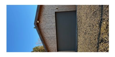 Fotografi av en fasade med en garasjeport og trepanelvegg.