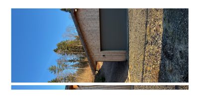 Fotografi av en moderne bygning med trefasade og garasjeport, sett fra utsiden mot en blå himmel.