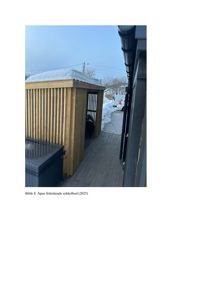 Fotografi av en åpen, frittstående sykkelbod med snø på taket og en tilhørende terrasse.