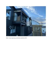 Fotografi av en moderne, mørk fasade med balkong og sykkelplass.