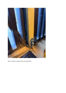 Fotografi som viser en åpen dobbel bod-dør sett innvendig, med fokus på dørkarmen og låsmekanismen.