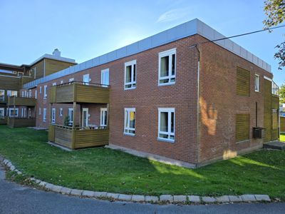 Fotografi av en eksisterende eller ferdigbygd leilighetsbygning med røde teglvegger, hvite vinduer og trebalconier.