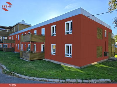 Fotografi av en ferdigbygd eller ferdigfasett bolig med rød fasade, hvite vinduer og treterasser.