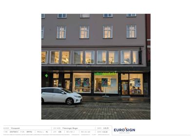 Fotografi av Vitusapotekets fasade på Fiskeritorget i Bergen, tatt om kvelden.