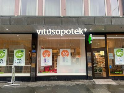 Fotografi av fasaden på en Vitusapotek-butikk med vindusutstillinger og inngang.