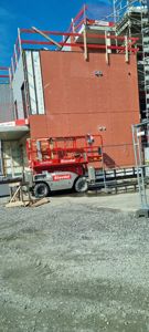 Fotografi av en byggeplass som viser fasaden på en bygning under oppføring med en heis i forgrunnen.