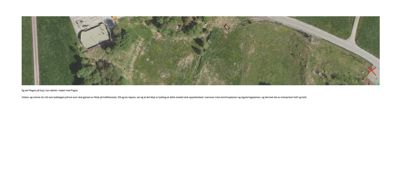 Flyfoto eller satellittbilde av et område med en bygning, veier og vegetasjon.