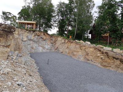 Fotografi av en byggeplass med en ny asfaltert vei og en delvis ferdigstilt bygning i bakgrunnen.