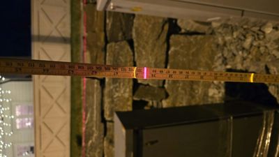 Fotografi av en steinvegg med en målebånd som strekker seg horisontalt over bildet.