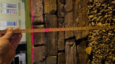 Fotografi av en vegg med steinpanel og en metallmålebånd som holder en måling.