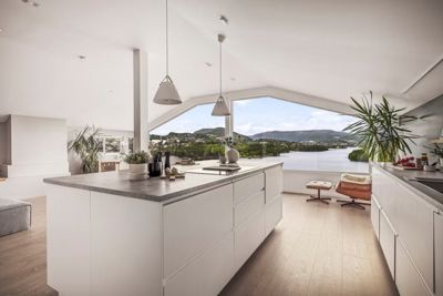 Fotografi av en moderne kjøkken- og stueplass med utsikt over vann og fjell.