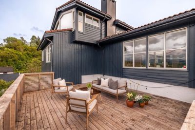 Fotografi av en terrasse med møbler foran en mørkeblå villa.