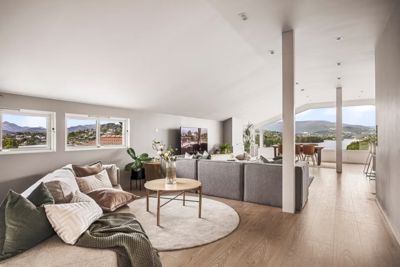 Fotografi av et moderne, innredet stue med utsikt over en by og fjord.