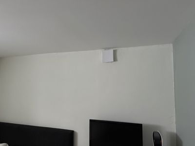 Fotografi av en hvit vegg i et rom, med en sort TV og en mørk sofa i forgrunnen.