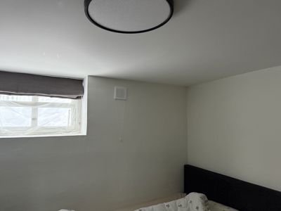 Fotografi av et soverom med en seng, et vindu og en taklampe.