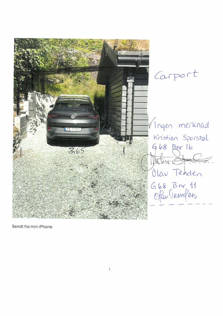 Fotografi av en carport med bil parkert under, sett fra bak. Bildet viser også en del av en bygning til høyre og en steinmur til venstre.