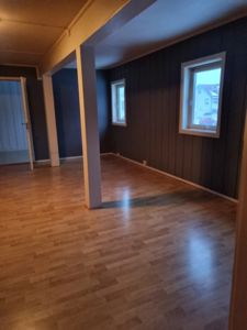 Fotografi av et tomt rom med gulv, vegger og vinduer.