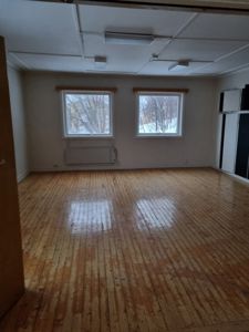 Fotografi av et tomt rom med gulv, vinduer og tak.
