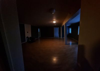 Fotografi av et mørkt, tomt rom med gulv, vegger, dører og vinduer synlig.