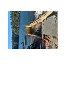 Fotografi av en byggeplass ved vannet med utstyr og materialer.