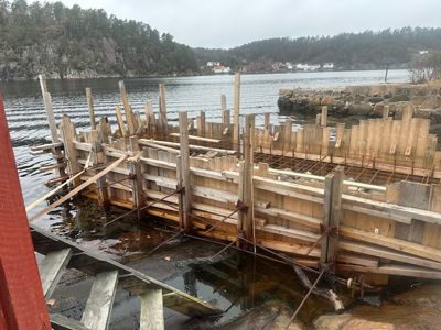 Fotografi av en betongform (slikke) i vannet, sannsynligvis for et fundament eller kai.