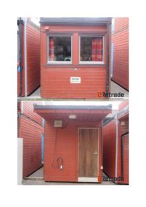 Fotografi av en liten, rød, modulær bygning (kanskje en container eller hytte) sett fra front og side. Bildet viser fasaden med vinduer, dør og omgivelsene.