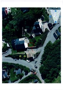 Flyfoto eller luftfotografi av et boligområde med en bygning og en vei. Bildet inneholder også en innfelt kartvisning i øvre høyre hjørne.