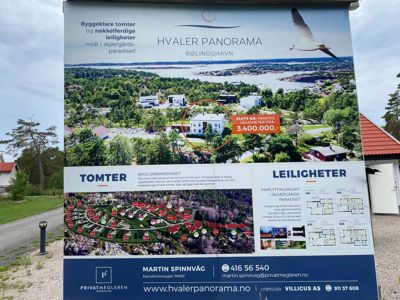 Fotografi av et reklameskilt for eiendommen 'Hvaler Panorama' som viser en situasjonsplan, etasjeplaner og en rendering.