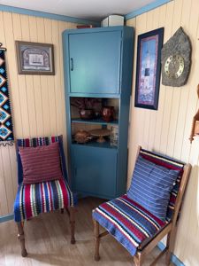 Fotografi av et innredet rom med to stoler, et skap og dekorasjoner på veggene.