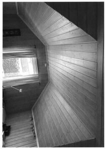 Sort-hvitt fotografi av et rom med panelvegger og et takvindue.