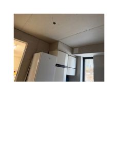 Fotografi av en kjøkkenrom i en bygning under oppføring eller renovering, med synlig betong og innredning.