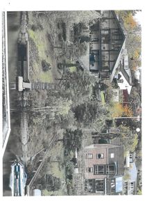 Fotografi av en bebygd kyststrøk med hus, trær og vann.