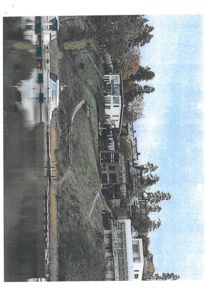 Fotografi av en rekkehusbebyggelse langs en vassdrag eller vei, sett fra en viss avstand.