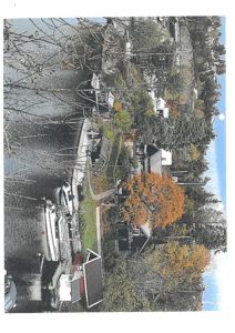 Fotografi av en bebyggelse langs et vann med båter og trehus.