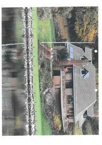 Fotografi av en villa med brikkfasade og takterreng, sett fra siden med vann i forgrunnen.