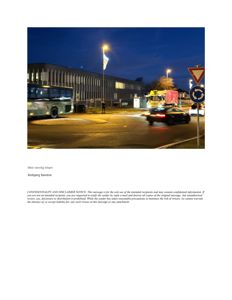 Fotografi av en bygning og gate ved kveldstid, inkludert kjøretøy og trafikkmerker.