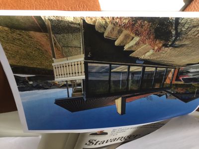 Fotografi av en moderne bygning med store vinduer og en terrasse, sett fra en vinkel.