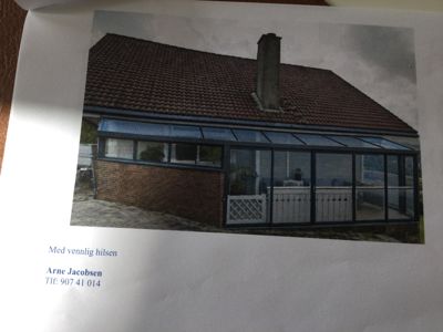 Fotografi av en eksisterende bygning med en tilbygget solrom eller veranda.