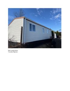 Fotografi av en hvit paneltelt med vinduer og tak, sett fra siden.