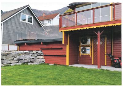 Fotografi av en rød og gul bygning sett fra siden, med en grå nabobygning i bakgrunnen.