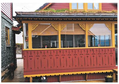 Fotografi av en bygning med rød og gul fasade, dekorative detaljer og et grønt tak.